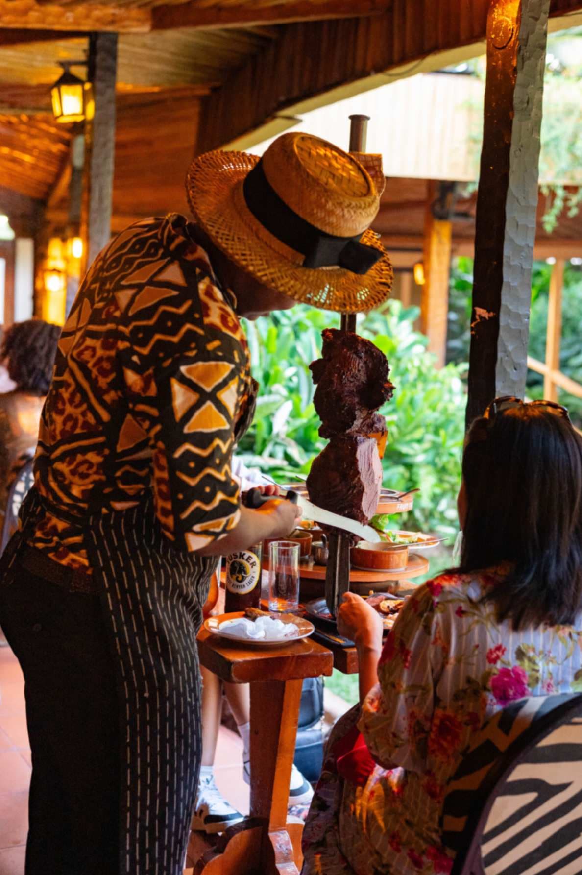 A carver using traditional Maasai swords to serve a rotating selection of roasted meats